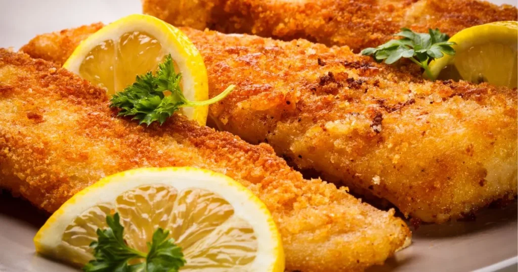 Close-up of crispy Southern Fried Fish whiting fillets with a golden-brown crust, garnished with fresh parsley and lemon wedges.